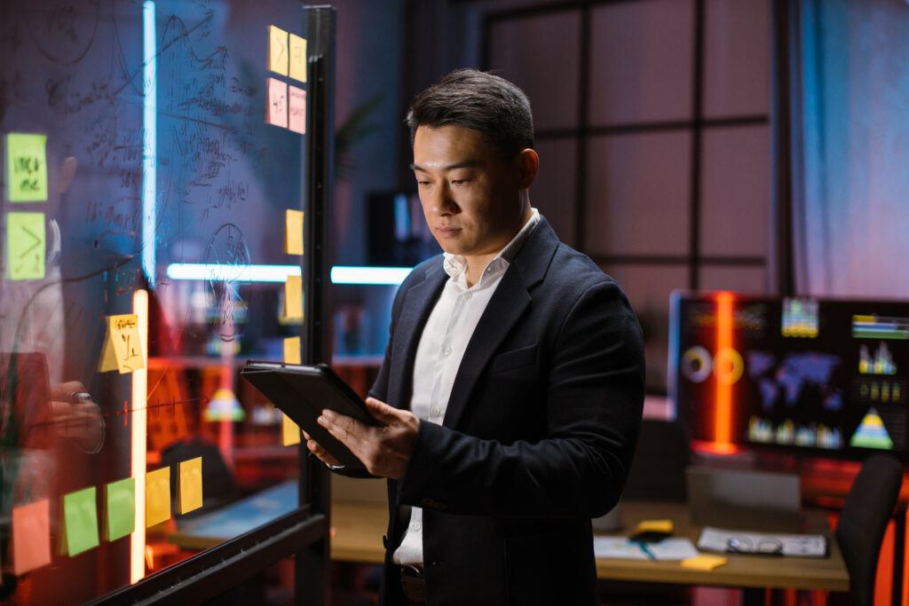 IT-Experte analysiert Daten und Strategien an einem digitalen Whiteboard mit Tablet