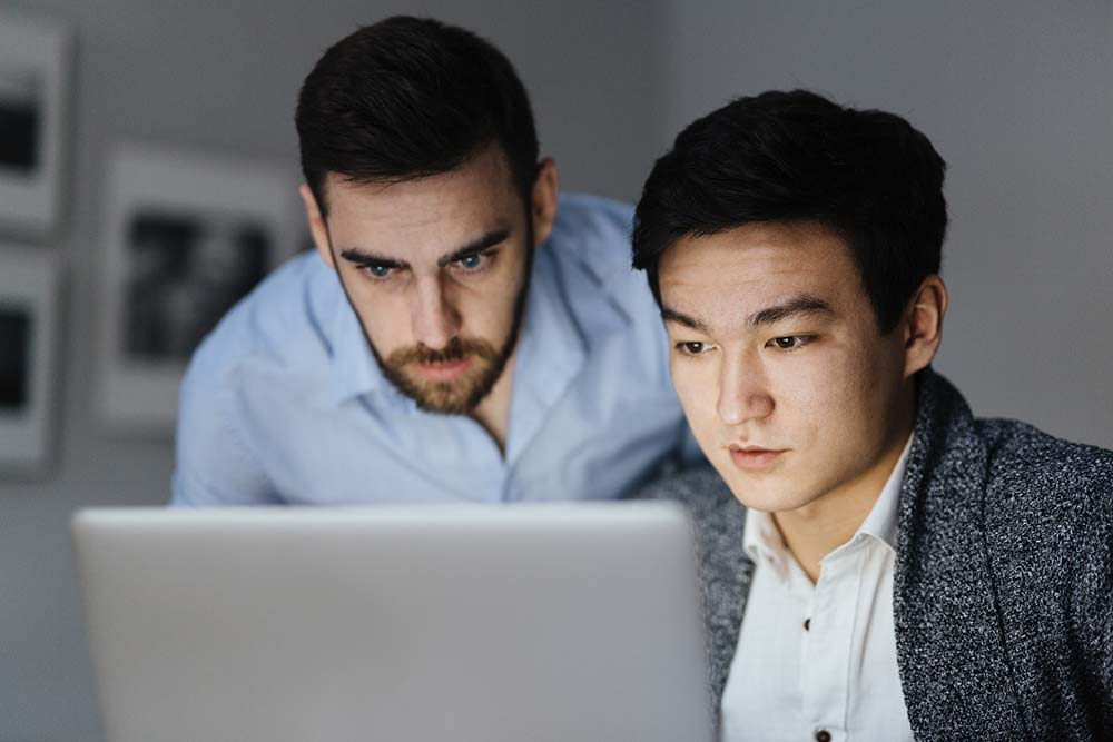 Zwei Mitarbeiter analysieren konzentriert sicherheitsrelevante Daten am Laptop